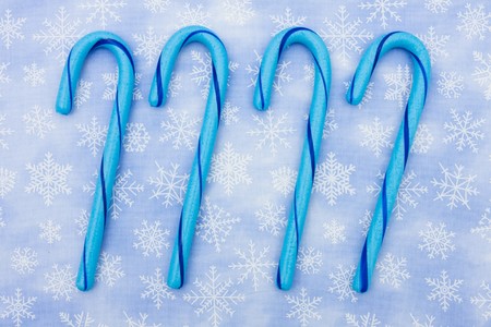 Blue candy canes sitting on a blue snowflake background, candy canesの写真素材
