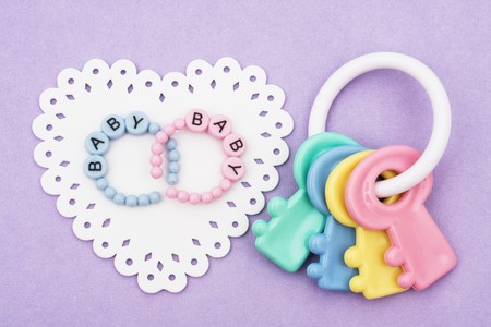 Baby bracelet with a rattle sitting on a white paper heart on purple background, baby bracelets