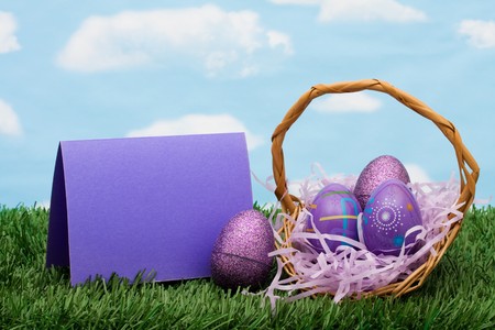 Colourful Easter eggs sitting in a basket with a blank card on green grass background, Easter basketの写真素材