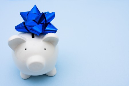 Piggy bank with blue ribbon bow sitting on a blue background, investment の写真素材