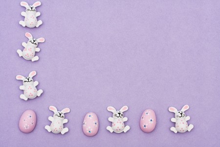 Easter bunnies and eggs sitting with a white  heart on purple background, Easter borderの写真素材