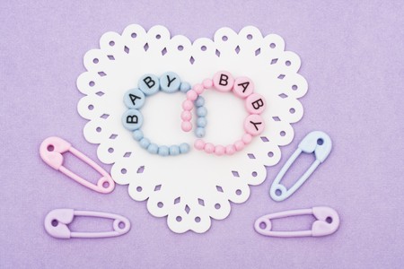 Baby bracelets and safety pins sitting on a white heart on purple background, baby braceletsの写真素材