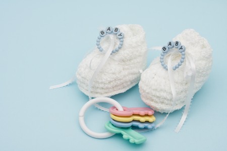 Baby booties with baby bracelet and rattle sitting on a blue background, baby bootiesの写真素材