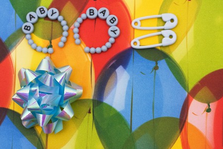 Blue ribbon with diaper pins and baby bracelet sitting on a balloon background, baby borderの写真素材