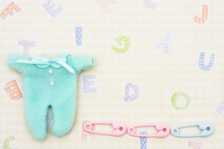 Baby sleeper with diaper pins sitting on a yellow alphabet background, baby sleeperの写真素材