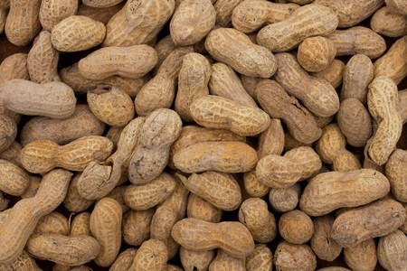 A pile of peanuts in the shell making border on a brown background, peanut border