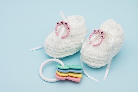 Baby booties with baby bracelet and rattle sitting on a blue background, baby bootiesの写真素材