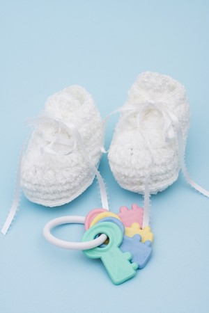 Baby booties and rattle sitting on a blue background, baby bootiesの写真素材