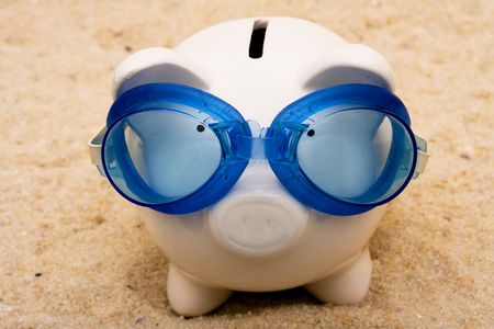 A piggy bank wearing swimming goggles on a sand background, vacation savingsの写真素材
