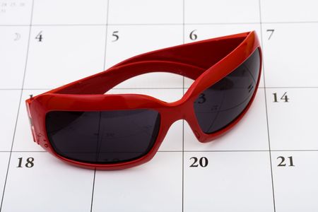 A pair of sunglasses sitting on a calendar background, vacation calendarの写真素材