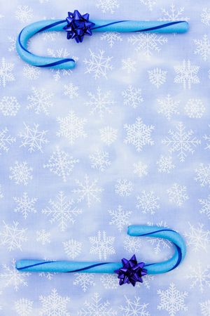 Blue candy canes with bow sitting on a blue snowflake background, candy canesの写真素材