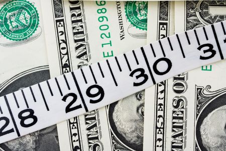 Measuring tape sitting on one dollar bill background, Costs of weight lossの写真素材