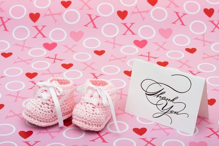 A white thank you card with baby booties on a pink love background, thank you note