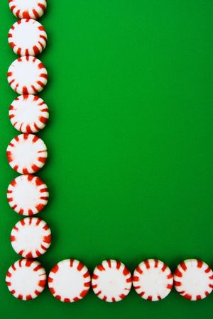 Red and white peppermints sitting on a green background, peppermint border