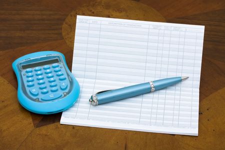 A blue calculator with pen and paper on a wooden table background, balancing your cheque book