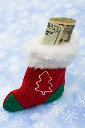 A Christmas stocking with cash in it sitting on a snowflake background, Christmas cashの写真素材