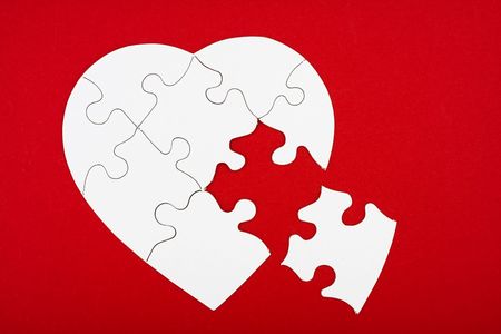 A white heart shape puzzle on a red background, heart shape puzzle