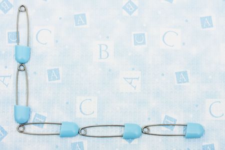 Blue diaper pins making a border on a blue alphabet background, diaper pin borderの写真素材