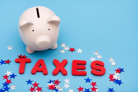 A piggy bank with the word taxes and stars on a blue background, Saving Money on Taxesの写真素材