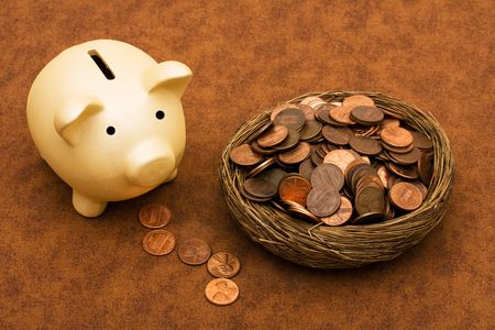 Piggy bank with a bowl of pennies on a brown textured background, seeing your savingsの写真素材