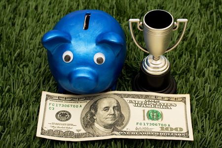 A blue piggy bank with a gold trophy sitting on grass background, winning with your savingsの写真素材