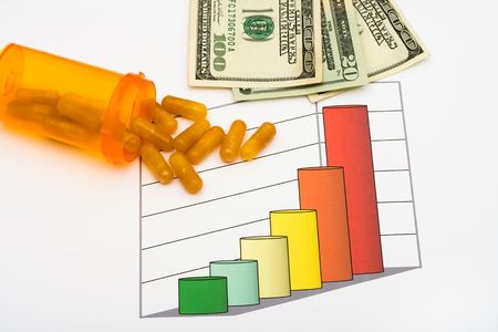 A one hundred dollar bill and pills on a graph that is on a white background, increased healthcare...
