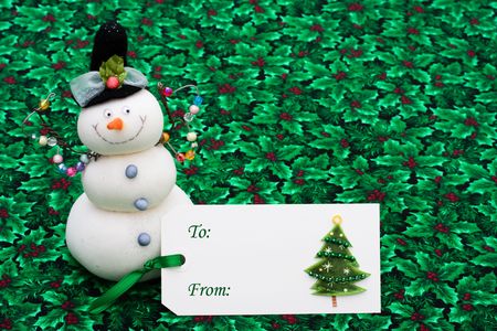 A blank gift tag with a snowman on a holly berry and leaf background, happy holidaysの写真素材