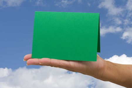 A blank card green card sitting in hands on a sky background, blank cardの写真素材