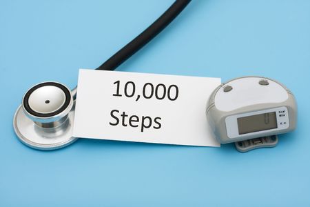 A stethoscope and a pedometer with a note on a blue background, walking for a healthy heart
