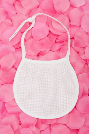 A baby bib sitting on a pink flower petal background, baby bibの写真素材