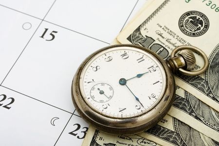 A pocket watch with hundred dollar bills sitting on a calendar background, time managementの写真素材