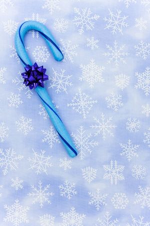 Blue candy cane with bow sitting on a blue snowflake background, candy caneの写真素材