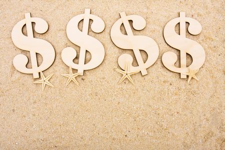A gold coloured dollar symbol sitting on a beach with starfish, vacation moneyの写真素材