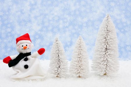 White evergreen trees sitting with a snowman on snow with a blue snowflake background, snowmanの写真素材