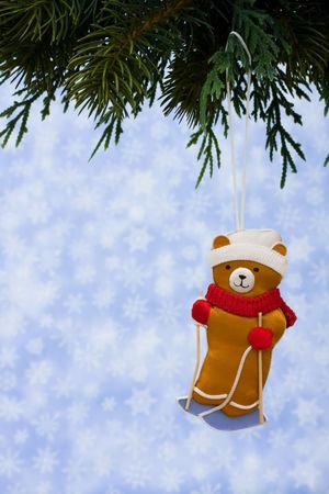 Teddy bear ornaments hanging on a tree on a blue snowflake backgroundの写真素材