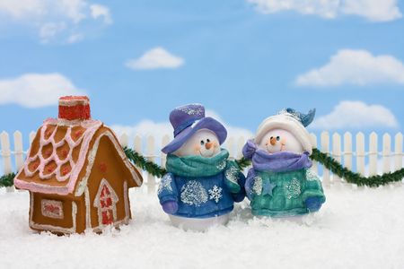 Gingerbread house on snow with a snowman and sky background, gingerbread houseの写真素材