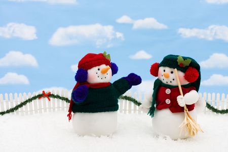 Two snowmen on a white picket fence with garland on a  sky background, gingerbread houseの写真素材