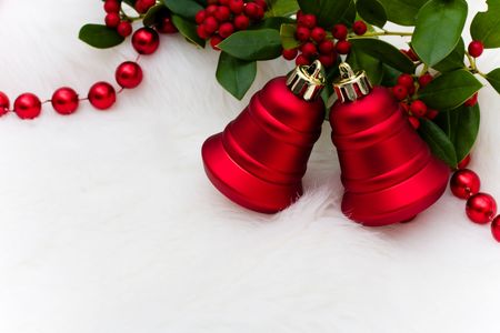Red bells and holly and berries on a white fur background, Christmas bellsの写真素材