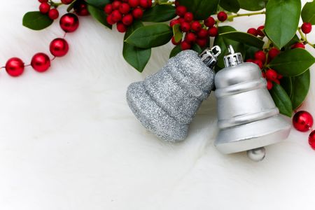 Silver bells and holly and berries on a white fur background, Christmas bellsの写真素材