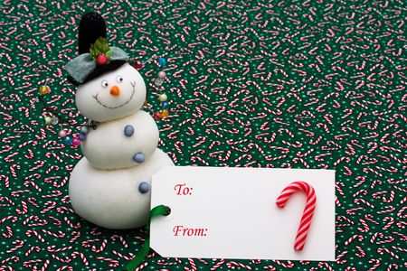 A blank gift tag with a snowman on a candy cane background, happy holidaysの写真素材