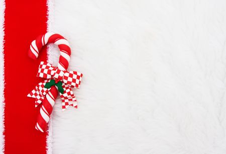 A candy cane with a red ribbon on a white fur backgroundの写真素材