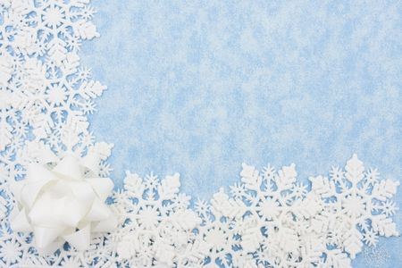 Snowflakes with white bow making a border on a blue backgroundの写真素材