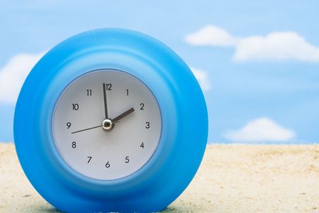 A blue clock sitting on a beach, vacation time