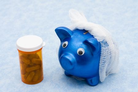 Piggy bank with a bandage over it and a bottle of billsの写真素材