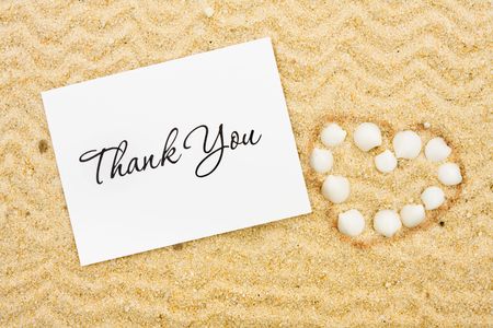 Seashells making a heart shape in the sand, Thank youの写真素材