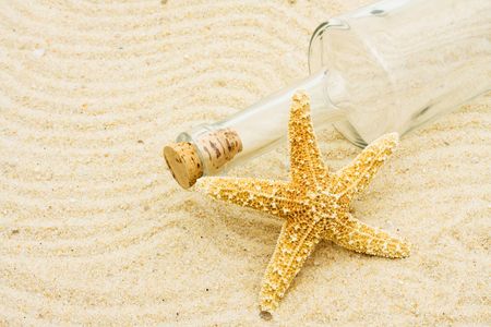 An empty bottle with a starfish in the sand, vacation の写真素材