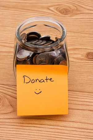 A jar full of change sitting on a wooden background, Please help by donating money