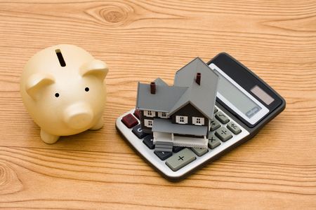 A piggy bank and a calculator sitting on a wooden background, mortgage calculatorの写真素材