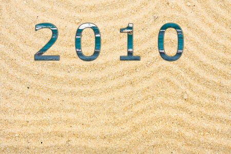 Sand with many lines drawn in it with 2010 written with water, beach backgroundの写真素材