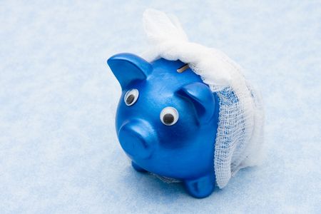Piggy bank with a bandage over it on a blue background, Increasing health care costsの写真素材